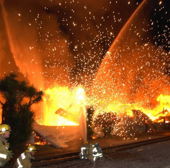 Los Angeles firefighters take cover as an explosion sends flames from an industrial building in South Los Angeles on Wednesday.